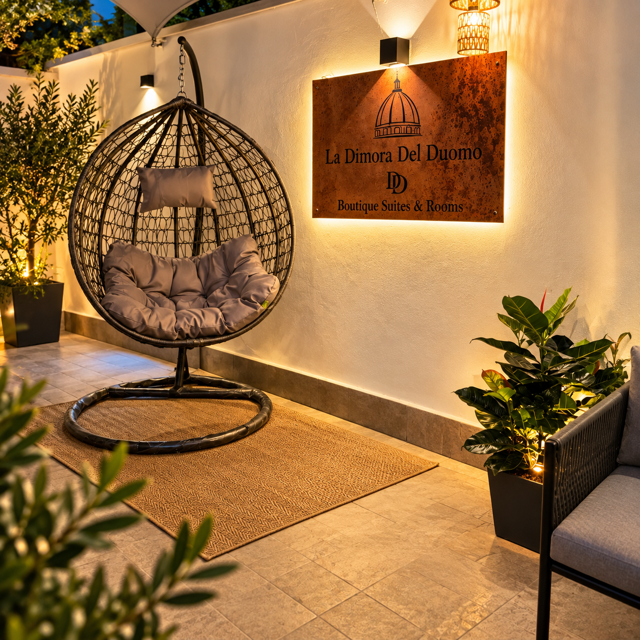Terrazza de La Dimora del Duomo con poltrona sospesa e insegna in corten retroilluminata